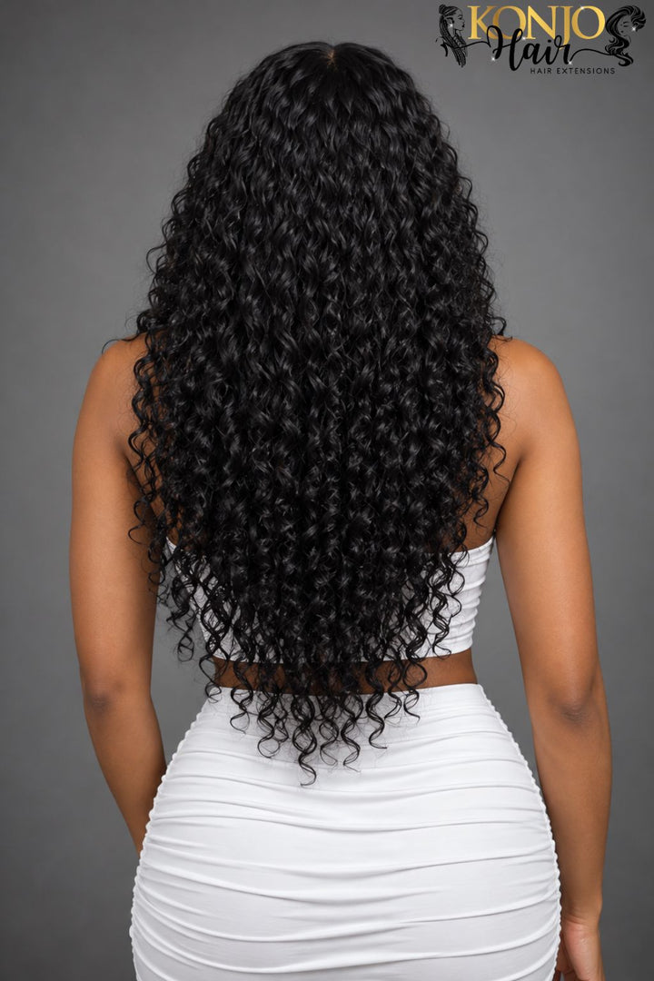 view of a woman wearing long black Burmese curly hair extensions, showcasing the hair length, natural volume, and defined curly texture.